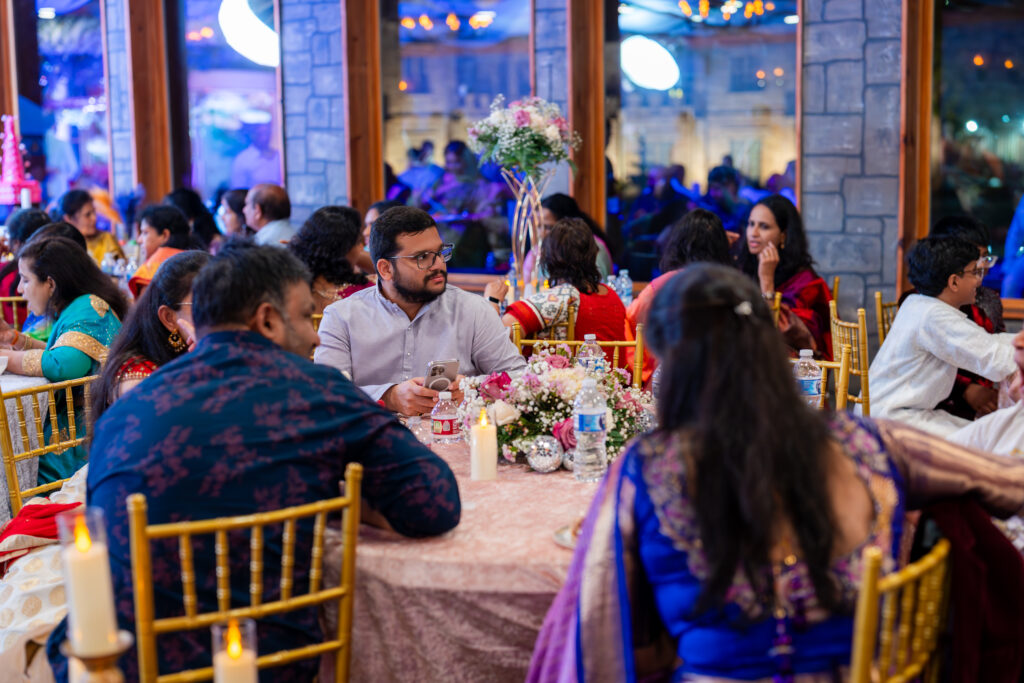 Guests seated around a decorated table at a wedding reception inside Castle Waterford, enjoying conversations.