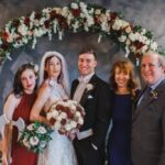 Bride and groom posing with family under floral arch at Castle Waterford wedding ceremony