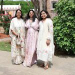 Three women posing together outdoors in elegant traditional Indian outfits