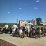 Outdoor wedding ceremony setup with guests seated facing Castle Waterford under clear blue sky