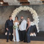 Bride and groom posing with guests under floral arch at Castle Waterford indoor wedding setup