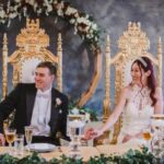 Bride and groom seated on golden royal chairs holding hands during wedding ceremony at Castle Waterford