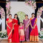 Family group posing together in traditional Indian attire at a wedding ceremony backdrop