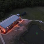 Aerial view of Castle Waterford event venue with illuminated building and lakeside setting at evening