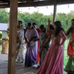 Traditional Indian women dancing together at a festive celebration wearing colorful sarees