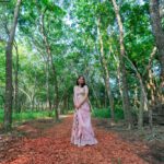 Woman in elegant dress standing on forest pathway surrounded by greenery at Castle Waterford