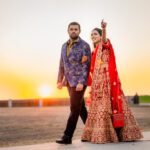 Couple in traditional Indian wedding attire walking at sunset during photoshoot at Castle Waterford