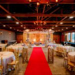Indoor wedding aisle with red carpet, banquet seating, and decorated stage at Castle Waterford