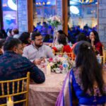 People sitting around a decorated table at a wedding or festive event enjoying dinner together