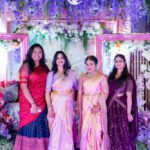 Group of women posing together in traditional Indian outfits at a decorated festive backdrop