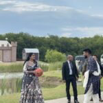 Guests in traditional attire interacting by lakeside at Castle Waterford wedding celebration