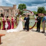 Bride and groom exchanging vows under circular floral arch at Castle Waterford outdoor wedding ceremony