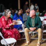 Guests in traditional attire sitting and talking during wedding ceremony at Castle Waterford
