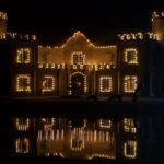 Castle Waterford illuminated with decorative lights at night with reflection in water
