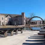 Castle Waterford outdoor seating area with benches and circular arch by lakeside