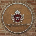 Castle Waterford logo emblem on brick wall showcasing brand identity