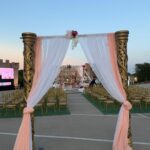 Decorated wedding entrance with draped fabric leading to outdoor seating and stage.