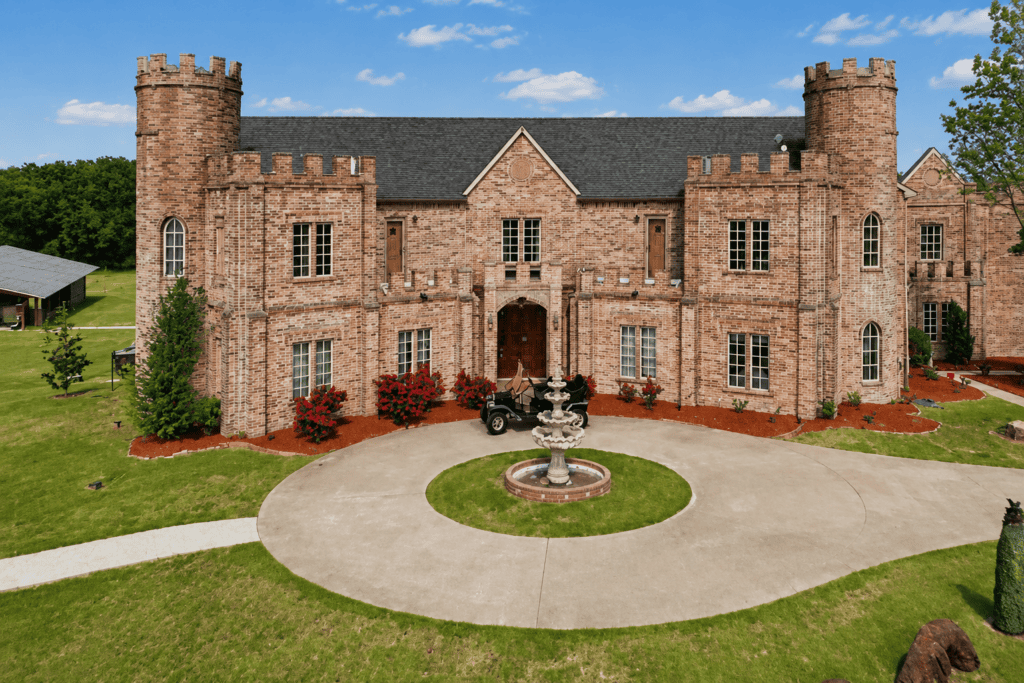 Front exterior view of Castle Waterford featuring a grand stone castle, circular fountain, landscaped grounds, and elegant architecture in Royse City, Texas.