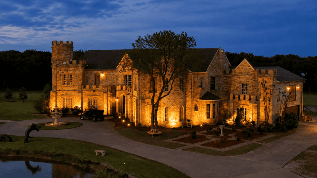 Castle wedding venue in Texas illuminated at night with landscaped grounds and pond